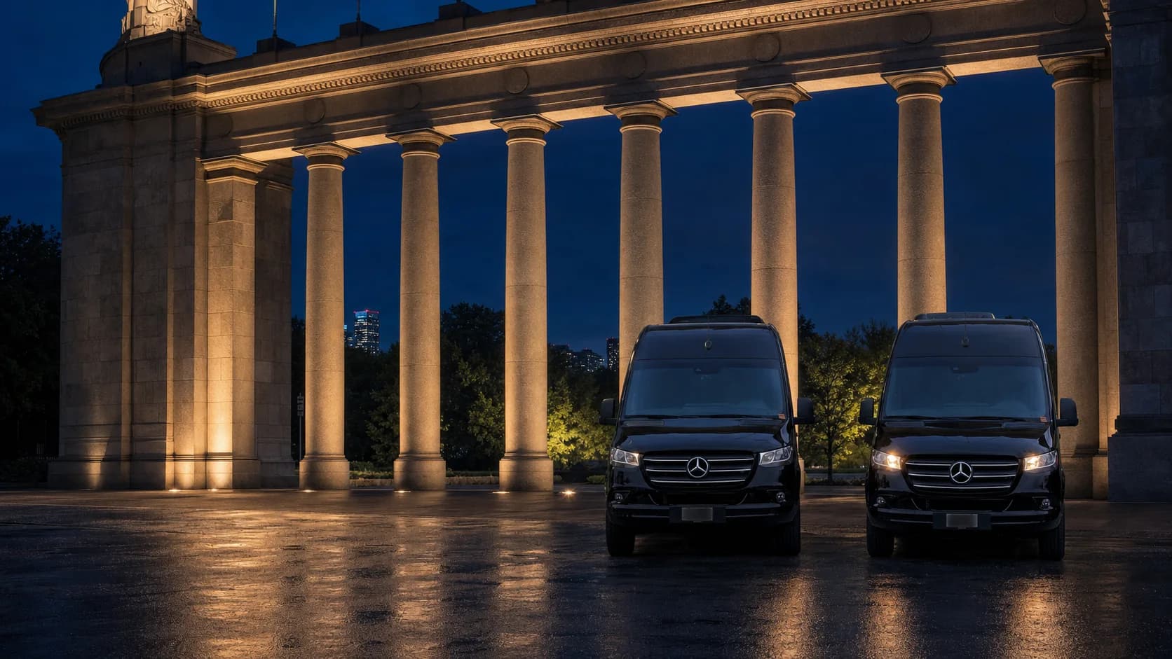 Two black Mercedes-Benz Sprinter vehicles positioned beneath illuminated columns