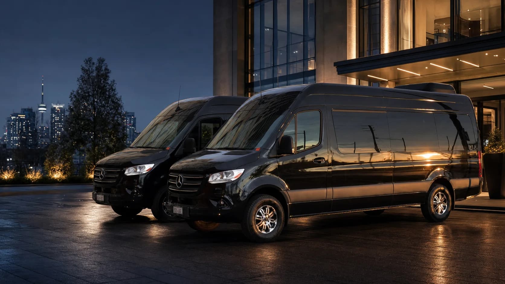 Two black Mercedes-Benz Sprinter vehicles outside contemporary Toronto architecture