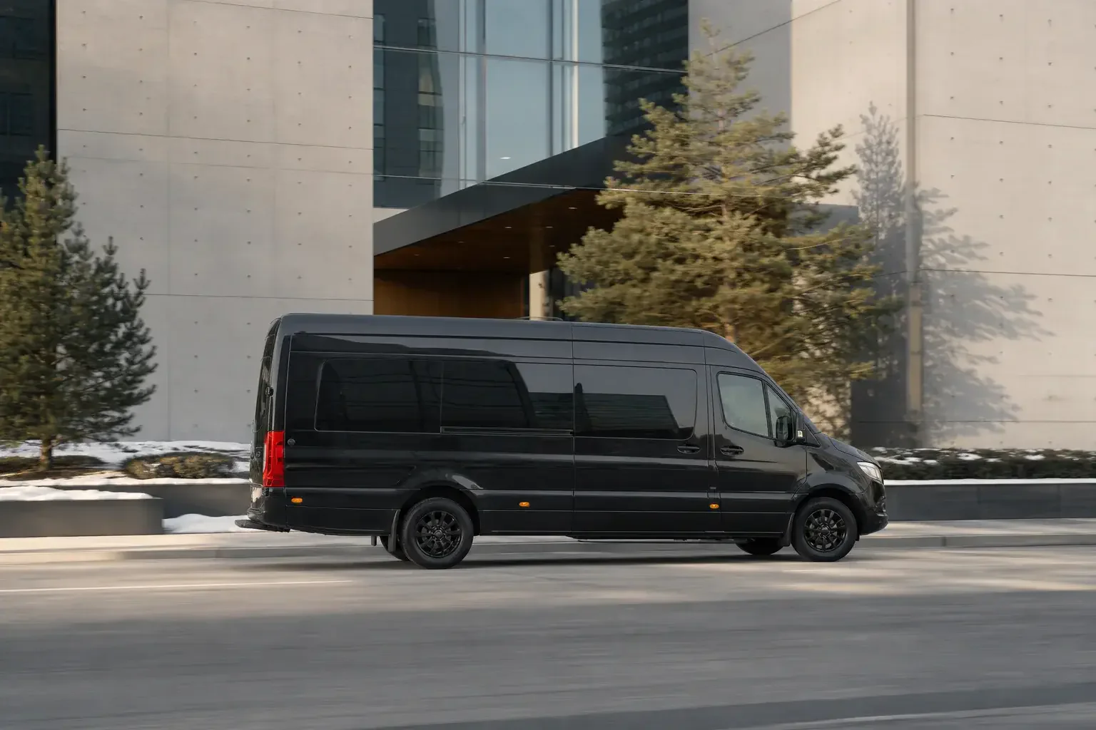 Black Mercedes-Benz Sprinter travelling past contemporary architecture